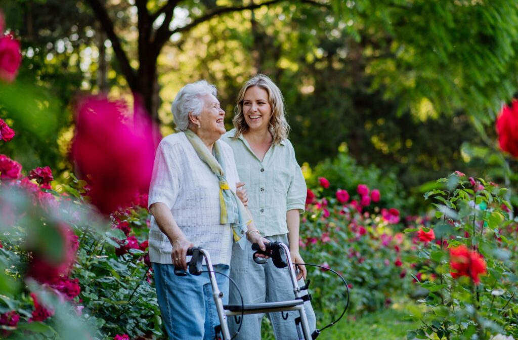 An older adult enjoying a stroll in the garden alongside her daughter.