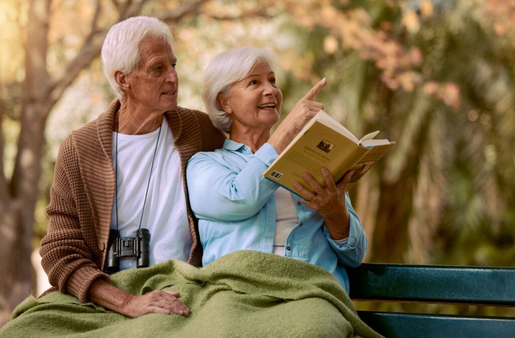 An order couple enjoying the outdoors while birdwatching together.