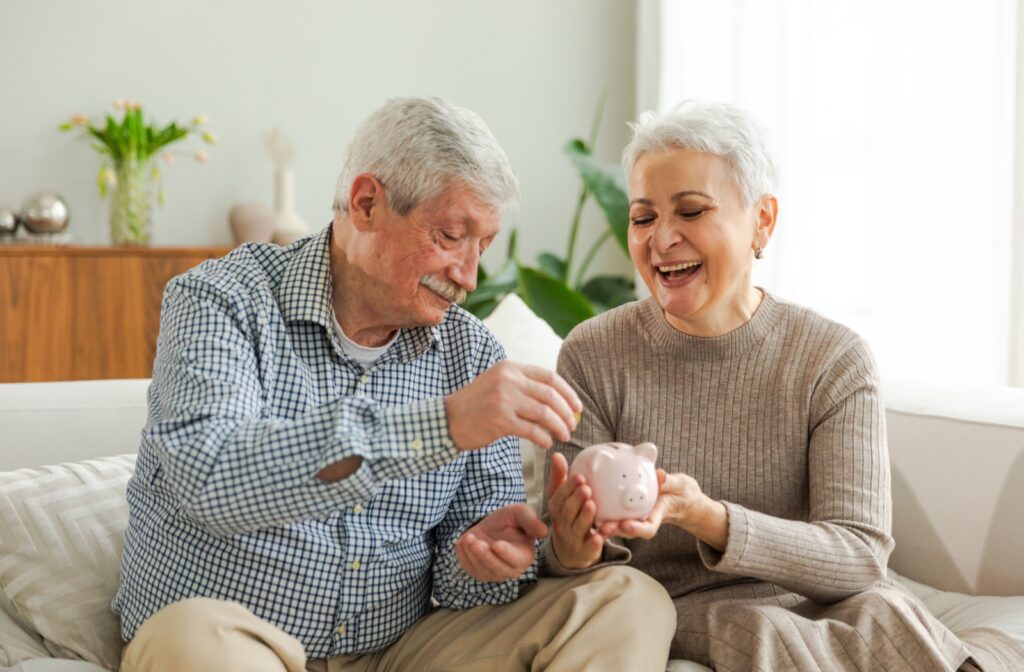 two seniors placing money in a piggy-bank to save for a retirement community.